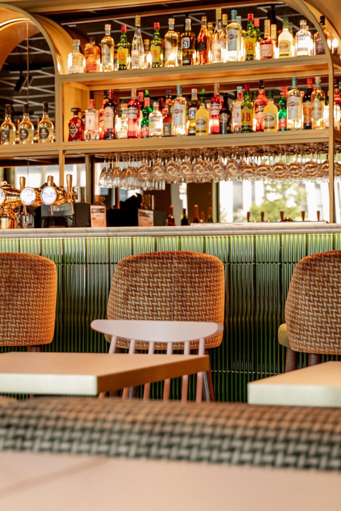 Les étagères à bouteilles du bar d'Italian Queen Meylan et la banquette vert bouteille