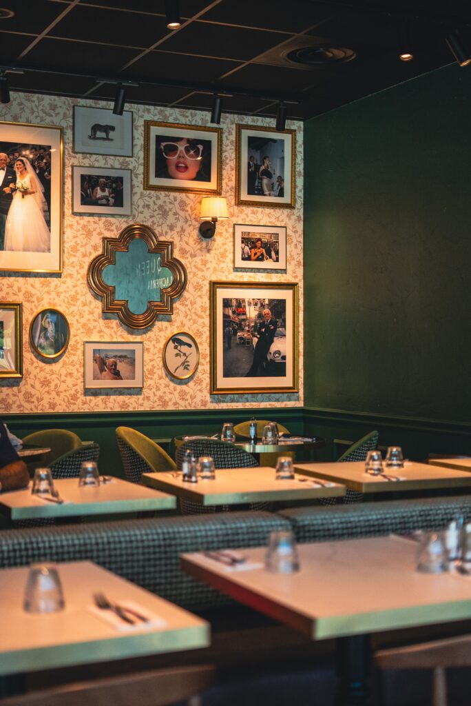 Le mur de photos encadrées, le miroir en arabesque et les tables dressées d'Italian Queen Meylan